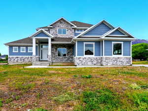 View of front of property with stone siding and a front yard