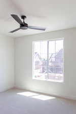 Carpeted empty room featuring ceiling fan and baseboards