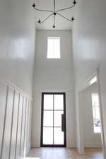 Entryway with a high ceiling, a chandelier, light wood-style flooring, and baseboards