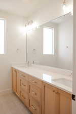 Full bathroom with double vanity, baseboards, and tile patterned floors