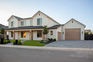 View of front of home with a standing seam roof, an attached garage, driveway, metal roof, and brick siding