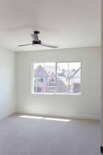 Carpeted empty room with a ceiling fan and baseboards
