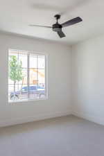 Empty room with light carpet, baseboards, and a ceiling fan