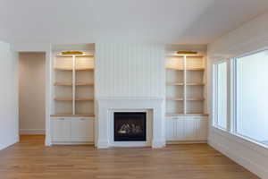 Unfurnished living room featuring light wood-style floors, a fireplace, plenty of natural light, and baseboards
