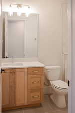 Bathroom with toilet, tile patterned floors, and vanity