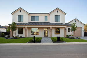 Modern farmhouse style home with a standing seam roof, a garage, a porch, a front lawn, and brick siding