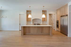 Kitchen with stainless steel appliances, light wood-style floors, light countertops, and tasteful backsplash