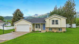 Split level home with a mountain view, a garage, brick siding, and driveway