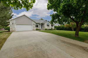 Ranch-style home with stone siding, driveway, a garage, and a front yard