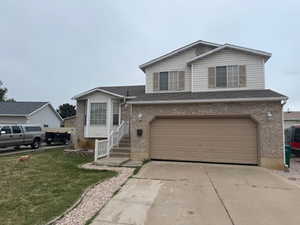 View of front of property with brick siding, an attached garage, concrete driveway, a front yard, and roof with shingles