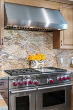 Kitchen with wall chimney range hood, double oven range, and decorative backsplash