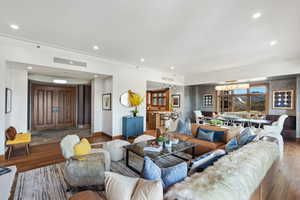 Living room with wood finished floors, baseboards, recessed lighting, and crown molding
