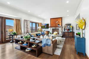 Living room featuring ornamental molding, healthy amount of natural light, recessed lighting, wood finished floors, and a fireplace