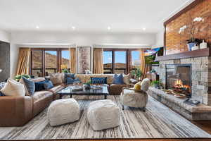 Living area with a stone fireplace, wood finished floors, ornamental molding, and recessed lighting