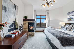 Bedroom with a stone fireplace, a chandelier, and baseboards