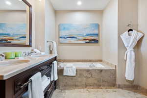 Full bathroom with double vanity, a garden tub, and recessed lighting