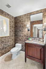 Half bathroom featuring baseboards, toilet, and vanity