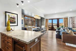 Kitchen with open floor plan, wine cooler, wood finished floors, light countertops, and brown cabinets