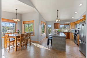 Kitchen with appliances with stainless steel finishes, concrete flooring, a kitchen island, a sink, and baseboards