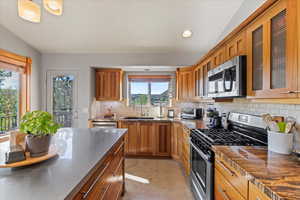 Kitchen with stainless steel appliances, a sink, decorative backsplash, brown cabinets, and recessed lighting