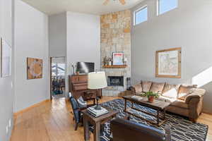 Living room with a high ceiling, healthy amount of natural light, wood finished floors, ceiling fan, and baseboards