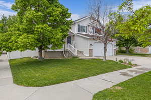View of front of home featuring driveway, a front yard, and an attached garage