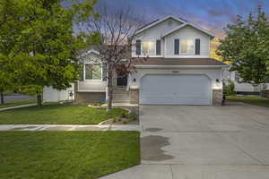 View of front of property with a garage, driveway, a front yard, and brick siding