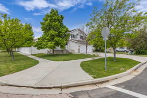 Corner lot view of property featuring an attached garage, roof mounted solar panels, and driveway
