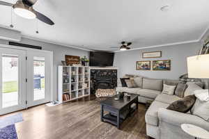 Living room with ceiling fan, wood finished floors, and a wood stove