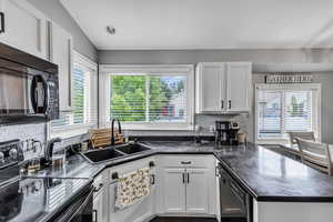 Kitchen with black appliances, a sink, healthy amount of natural light, and backsplash