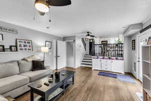 Living area featuring ceiling fan, stairs, wood finished floors, and baseboards