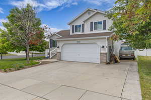 Traditional home featuring driveway, an attached garage, a front lawn, and brick siding
