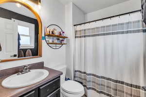 Primary suite  bathroom featuring toilet, vanity, and curtained shower