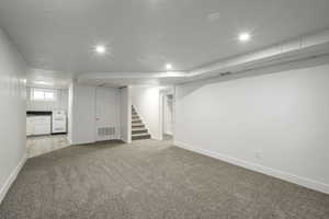 Below grade area with light carpet, baseboards, stairway, and recessed lighting