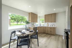 Kitchen with appliances with stainless steel finishes, a sink, light countertops, tasteful backsplash, and light wood-type flooring