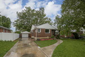 Bungalow-style house featuring brick siding, driveway, an outbuilding, and a detached garage
