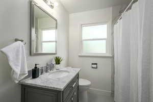 Bathroom featuring vanity, toilet, and baseboards