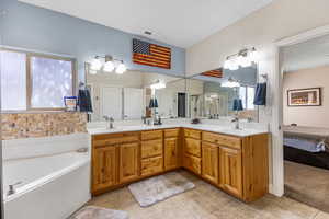 Ensuite bathroom featuring a garden tub, tile patterned floors, double vanity, and a stall shower