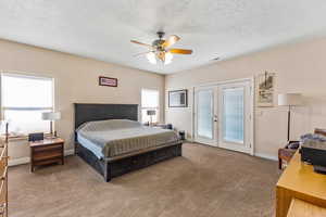 Bedroom with french doors, access to exterior, carpet floors, baseboards, and a textured ceiling