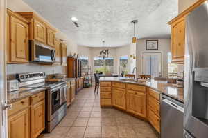 Kitchen featuring appliances with stainless steel finishes, a sink, a peninsula, plenty of natural light, and a textured ceiling