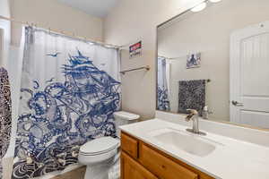 Bathroom with toilet, vanity, tile patterned floors, and a shower with curtain
