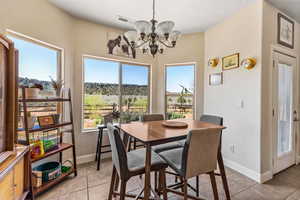 Dining space with a chandelier, light tile patterned floors, baseboards, and a textured ceiling