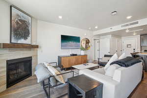 Living area with wood finished floors, recessed lighting, and a tile fireplace