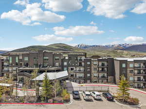 View of apartment building / complex featuring a mountain view and uncovered parking