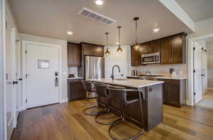 Kitchen featuring stainless steel appliances, a sink, dark brown cabinets, and recessed lighting