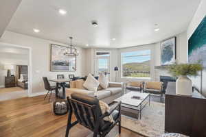 Living area featuring wood-type flooring, a chandelier, a glass covered fireplace, recessed lighting, and baseboards