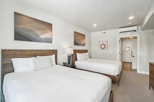 Bedroom featuring a wall mounted AC, recessed lighting, and baseboards