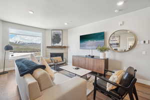 Living room with baseboards, a glass covered fireplace, recessed lighting, and wood finished floors