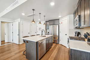 Kitchen featuring a sink, premium appliances, light wood-style flooring, a breakfast bar, and recessed lighting