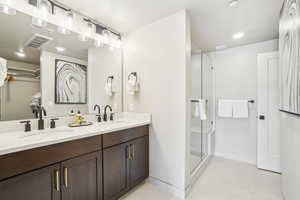 Bathroom with tile patterned flooring, a shower stall, double vanity, baseboards, and recessed lighting